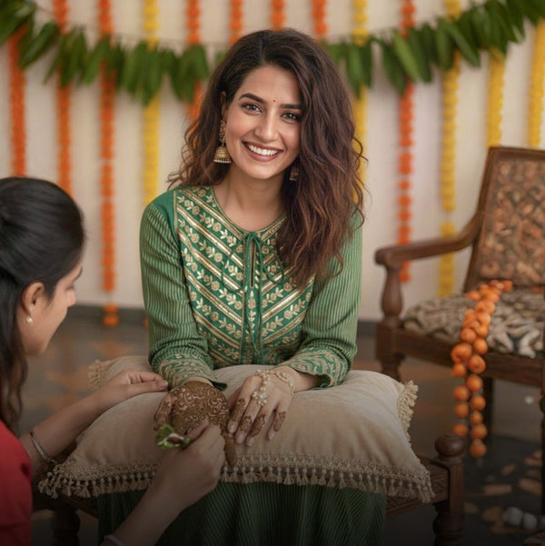 Woman in a green traditional outfit sitting on a cushion, celebrating mehendi ceremoney