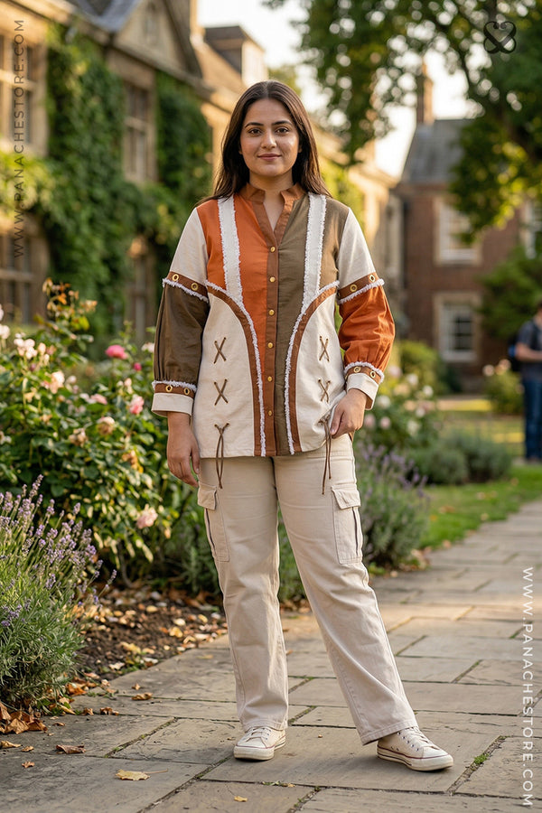 Woman standing outdoors in a garden wearing a patterned jacket and beige pants.