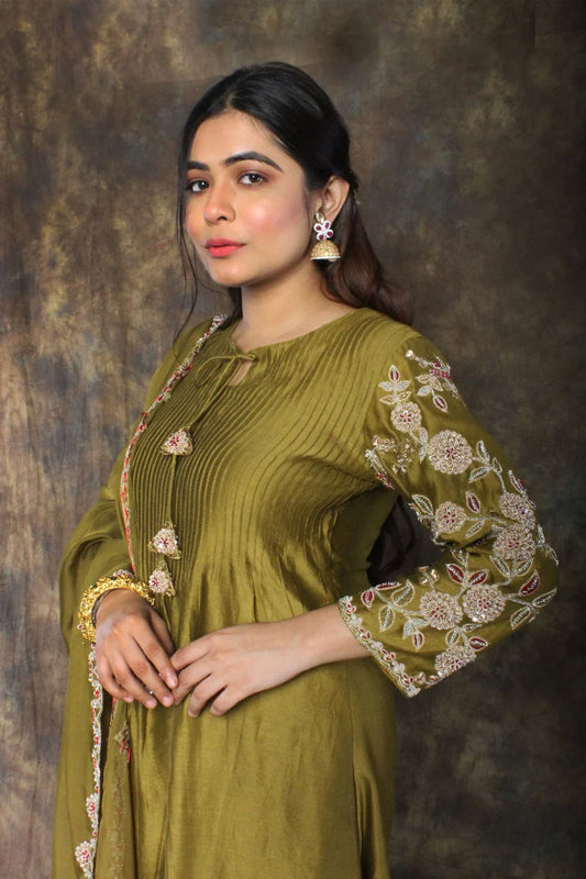 Woman wearing a henna green salwar suit and dupatta with a textured brown background